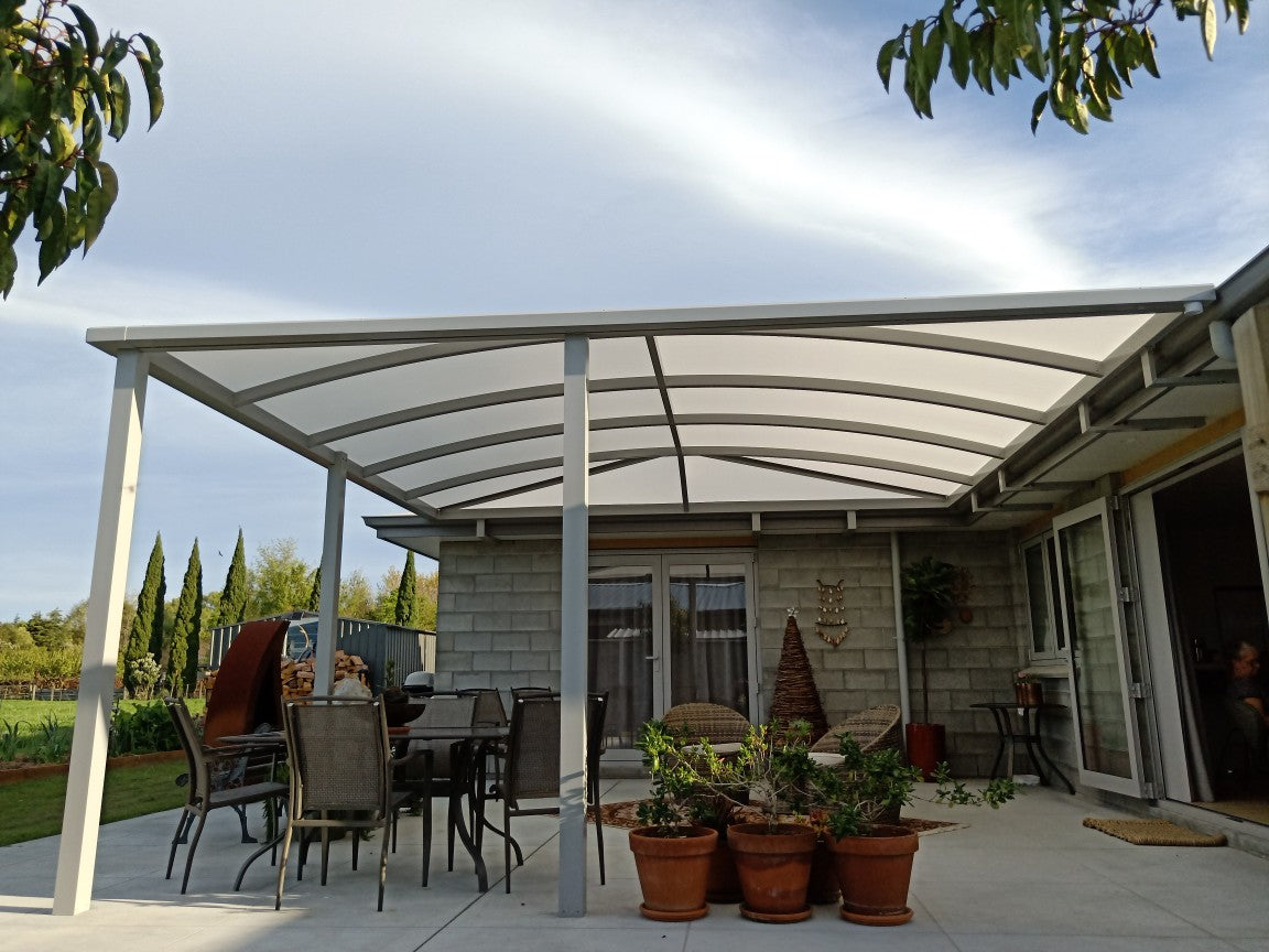Outdoor patio with a pergola, furniture, and potted plants on a clear day.